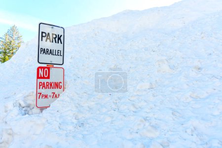 Photo for No Parking and Park Parallel signs in a deep snowdrift. Reminder to skiers and snowboarders of the park's boundaries and safety guidelines. - Royalty Free Image