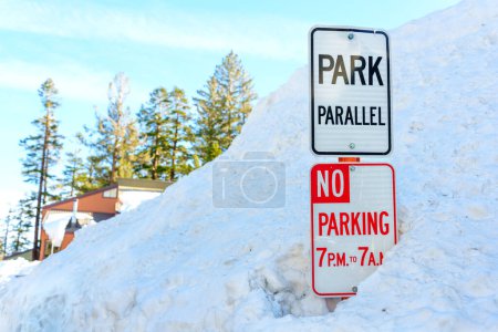 Photo for Winter Park Safety: No Parking and Park Parallel signs covered with snow. Reminder to skiers and snowboarders of the park's boundaries and safety guidelines. - Royalty Free Image
