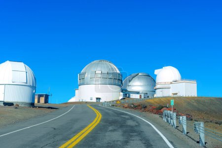 Photo for World-renowned astronomical research facilities at the summit of Mauna Kea, surrounded by a sea of blue sky and accessible via a winding road. - Royalty Free Image