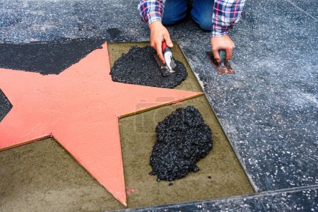 Worker placing terrazzo pavement around a star on the Walk of Fame in Hollywood.