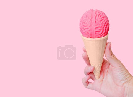 Photo for Hand holding a waffle cone filled with a human brain model isolated on pink background. Creative brain freeze concept. - Royalty Free Image