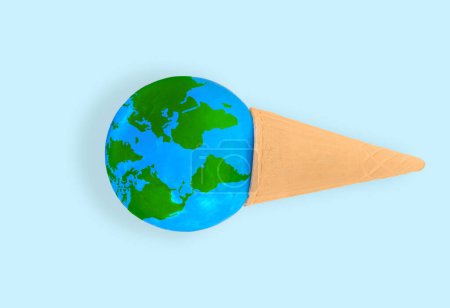 Téléchargez les photos : Globe niché à l'intérieur d'un cône de gaufre isolé sur fond bleu. Désir créatif et désir d'explorer le monde. - en image libre de droit