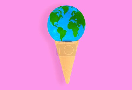 Téléchargez les photos : Globe miniature placé à l'intérieur d'un cône de gaufre croustillant isolé sur fond rose. Voyage, curiosité et joie de découvrir de nouvelles cultures et destinations. - en image libre de droit