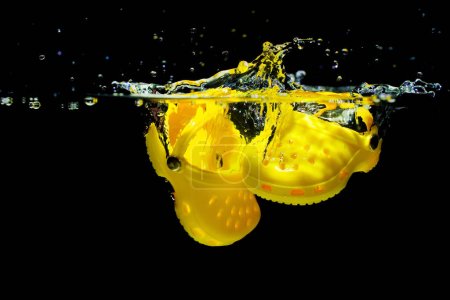 Photo for Kyiv, Ukraine - June 6, 2023: Yellow Crocs Submerged in Water with Splashes - Royalty Free Image