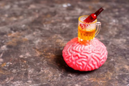 Foto de Taza de cerveza en miniatura y botella de cerveza encima de un modelo anatómico del cerebro. Alcoholismo, adicción, salud mental y búsqueda de ayuda y apoyo para la recuperación. - Imagen libre de derechos