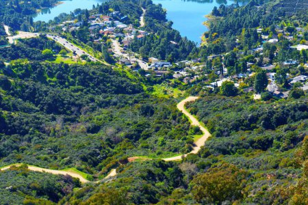 Foto de Lush green hill with a winding trail leading to the iconic Hollywood Reservoir in Los Angeles seen from an elevated viewpoint. - Imagen libre de derechos