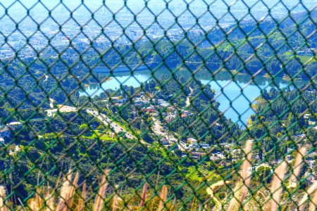 Foto de Vista aérea del embalse de Hollywood, los alrededores y la ciudad de Los Ángeles a través de una valla de malla de diamantes desde una ubicación en la cima de una colina. - Imagen libre de derechos