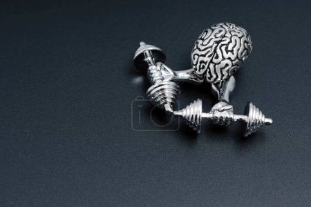 Photo for Close-up of a steel model of a human brain having a training session with heavy dumbbells isolated on black background with copy space. - Royalty Free Image