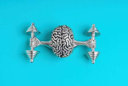 Photo for Metal human brain figurine lifting heavy dumbbells with strong arms, top view. Mind exercising related concept. - Royalty Free Image