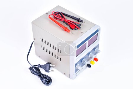Top-side view of a lab DC power supply unit with Leads and wires isolated on white.