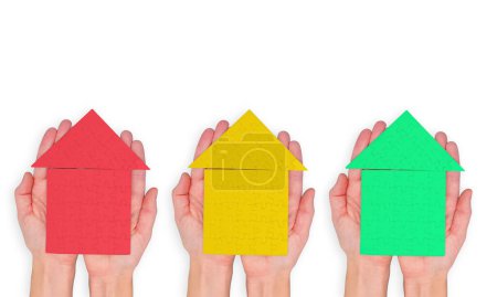 Top view of red, yellow and green jigsaw puzzle houses in hands isolated on white background. Vibrant development and marketing concept.