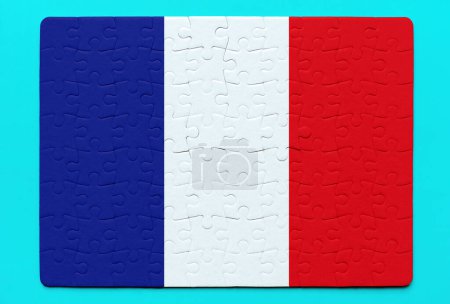Assembled French flag jigsaw puzzle rests on a vibrant blue background. Unity, diversity and cultural identity related concept.