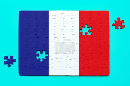 Two remaining pieces lie beside a French flag puzzle. Unity and accomplishment related concept.