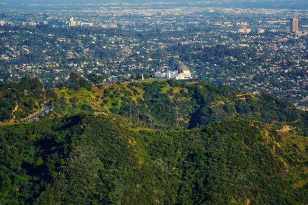 Téléchargez les photos : Observatoire Griffith vu d'un point de vue d'oiseau, niché au milieu de collines verdoyantes avec l'horizon de la ville au loin. - en image libre de droit
