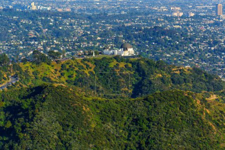 Téléchargez les photos : Observatoire Griffith vu d'en haut, perché au sommet de collines verdoyantes sur fond de paysage urbain par une journée tranquille d'avril. - en image libre de droit