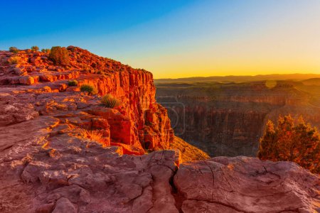 falaise robuste du Grand Canyon avec diverses couches de roches sédimentaires visibles, surplombant un canyon profond avec des murs ombragés sous un ciel dégradé.