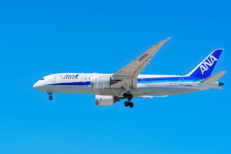 Photo for Los Angeles, California - April 9, 2024: Side view of an ANA (All Nippon Airways) plane flying in the blue sky, captured from Los Angeles International Airport. - Royalty Free Image