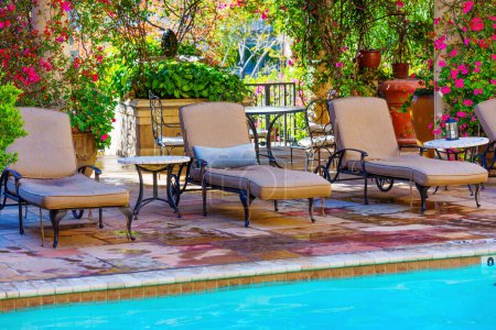 Ajuste sereno junto a la piscina con cómodas tumbonas y flores vibrantes.