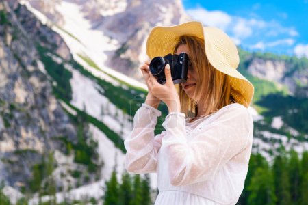 Foto de Fotógrafo de viaje con un vestido blanco y sombrero tomando una foto de los increíbles Alpes Dolomitas, Italia - Imagen libre de derechos