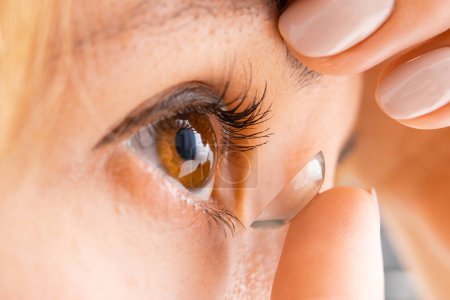 Close up young woman wearing a contact eye lens for vision improvement. Eye care concept