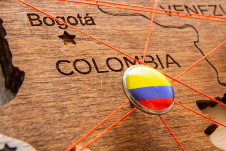 Photo for Colombia flag on the pushpin with red thread showed the paths of movement or areas of influence in the global economy on the wooden map. Planning of traveling or logistic concept. Network connection. - Royalty Free Image
