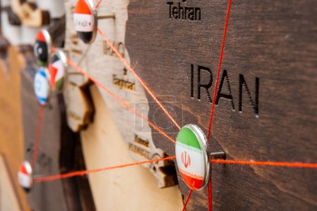 Photo for Iran flag on the pushpin with red thread showed the paths of movement or areas of influence in the global economy on the wooden map. Planning of traveling or logistic concept. Networks connection - Royalty Free Image