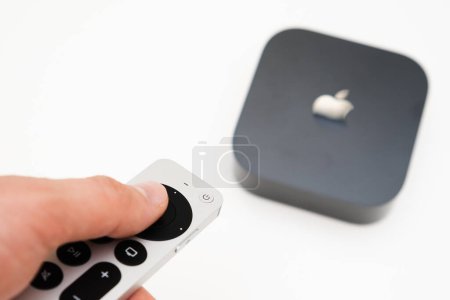 Téléchargez les photos : Man hand switches on the new black Apple TV 4K media streaming using remote controller, February 2023, Prague, Czech Republic - en image libre de droit
