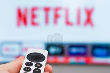 Photo for Netflix on Apple TV showing on the screen of TV. Man hands switch on television using remote controller, Fabruary 2023, Prague, Czech Republic. - Royalty Free Image