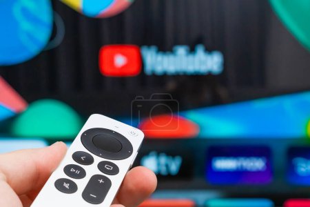 Photo for Youtube on Apple TV showing on the screen of TV. Man hands switch on television using remote controller, Fabruary 2023, Prague, Czech Republic. - Royalty Free Image