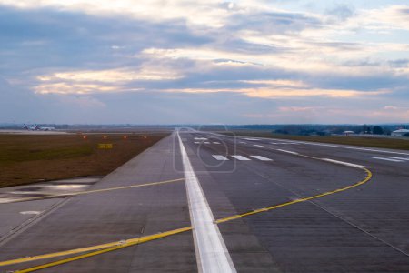 In der Flughafenumgebung ragt eine lange und ungehinderte Landebahn in die Ferne, die mit markanten Flugzeugmarkierungen und unverwechselbaren Wegen für nahtlose Starts und Landungen geschmückt ist..
