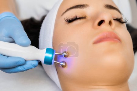 Photo for Application of microcurrent massage device on female face by cosmetologist. - Royalty Free Image