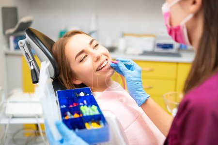 Téléchargez les photos : Dentiste nettoie les dents avec une brosse interdentaire pour les jeunes patients à la clinique de stomatologie - en image libre de droit