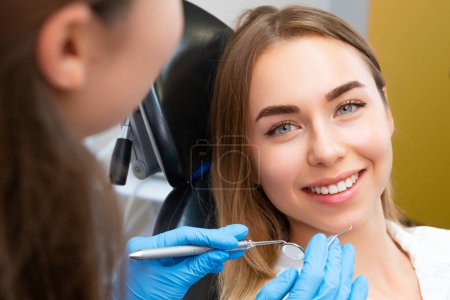 Photo for Brown-haired young woman preparing for dental procedure with dentist at private clinic appointment. Woman wants to cure teeth and have even smile - Royalty Free Image