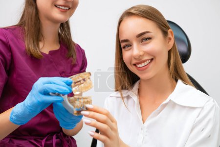 Photo for Dentist in medical gloves hold human jaw layout describing therapy to patient - Royalty Free Image