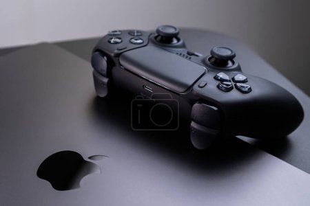 Photo for BERLIN , GERMANY - JANUARY 14 2024: A detailed view of the DualSense controller, designed for gaming on an Apple MacBook Pro Space Black. - Royalty Free Image