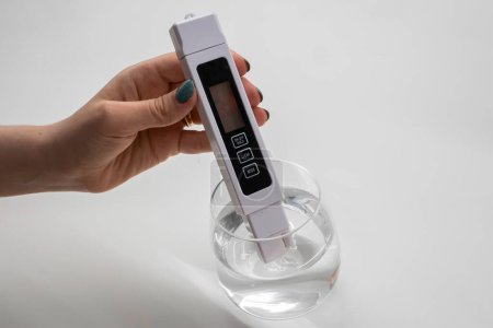 Woman uses a digital conductivity meter to check the purity of water. 