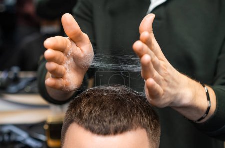 Téléchargez les photos : Coiffeur ajuste les cheveux fraîchement coupés du client dans le gros plan du salon de coiffure. styliste prudent tousles coupe de cheveux servant l'homme dans le salon de toilettage - en image libre de droit