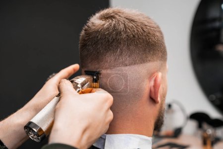 Téléchargez les photos : Rasage de l'occiput masculin par un coiffeur dans le salon de coiffure - en image libre de droit