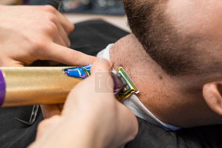 Téléchargez les photos : At the barbershop, the master effortlessly trims the clients beard using an automatic trimmer - en image libre de droit