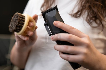 Téléchargez les photos : Woman barber holding trimmer and brush in her hands in barbershop. - en image libre de droit