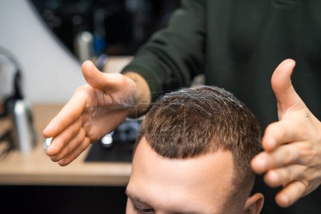Close up barber hands styling clients hair in barbershop. 