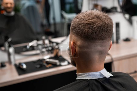 Client sitting after cutting hair in the barbershop.