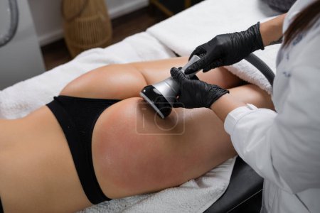 A young woman receiving ultrasound cavitation treatment for body contouring