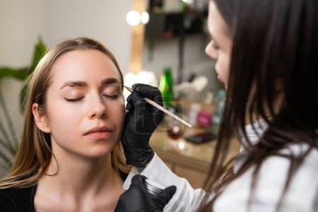 Schönheitsmeisterin skizziert Kontur für Brauenkorrektur im Schönheitssalon