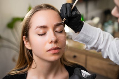 Schönheitsspezialist zeichnet Kontur für Augenbrauenkorrektur im Schönheitssalon