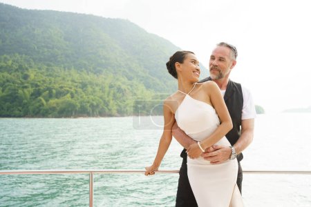 Téléchargez les photos : Heureux couple blanc asiatique et caucasien célébrant leur anniversaire de mariage ensemble sur le yacht. - en image libre de droit