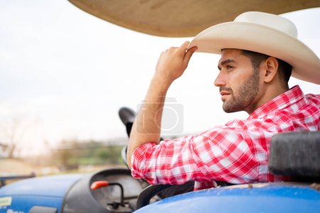 Photo for Handsome Middle East Asian man sitting on tractor and relaxing. Male farmer wearing a hat and relaxing on tractor. - Royalty Free Image