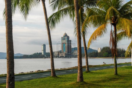 Foto de Una vista de la Torre Kinabalu, también conocido como Centro Administrativo Estatal de Sabah, desde un parque con palmeras en Kota Kinabalu, Sabah, Malasia - Imagen libre de derechos