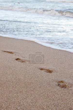 empreintes de pas dans le sable au bord de la mer
