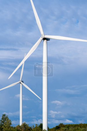 Windmühlenfarm zwischen Feldern und kleinen Bäumen. Europäische Umweltinitiative. Erhaltung von Energie und fossilen Ressourcen. Null ökologischer Fußabdruck